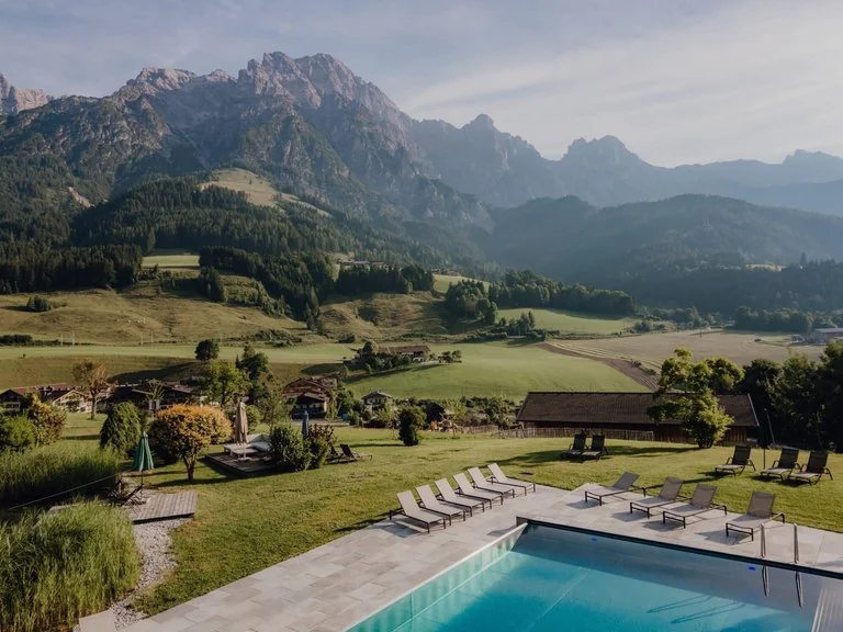Resort mit Pool vor einer Bergkulisse